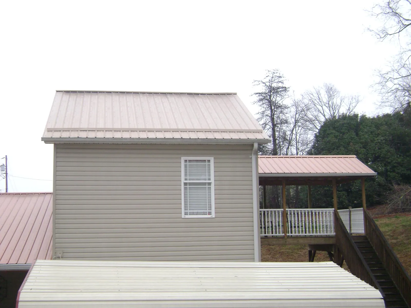 Tan metal roofs on a two story addition and attached porch, from a Roof Replacement job in Irvine